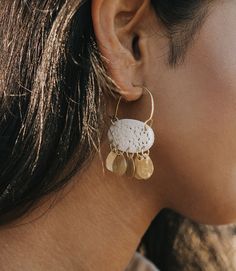 Our Charu collection combines cruelty free, ethically sourced bones featuring hand carved lace filigree work and shiny, gold finish brass elements in exquisite, boho chic designs. These bone earrings are expertly handcrafted by artisans in Old Delhi. Artisans utilize traditional Indian jewelry craft tools and techniques to skillfully transform local and upcycled materials into modern designs. The intricate hand worked filigree on this piece is a testament to their mastery of the craft, passed on White Bohemian Earrings With Intricate Design, White Bohemian Filigree Earrings, Brass Filigree Dangle Hoop Earrings, White Bohemian Brass Earrings, Etched Brass Drop Earrings, Etched Brass Earrings, Brass Filigree Chandelier Dangle Earrings, Bohemian Brass Jewelry With Fair Trade Details, Bohemian Etched Brass Earrings