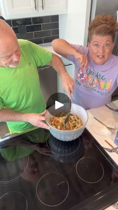 an older man and woman preparing food on the stove top in their kitchen, one is holding a pan