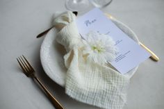 a white plate topped with a flower next to a fork and knife