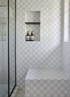 a white tiled bathroom with two bottles on the shelf