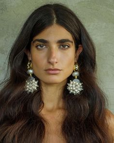 a woman with long brown hair and earrings on her head is looking at the camera