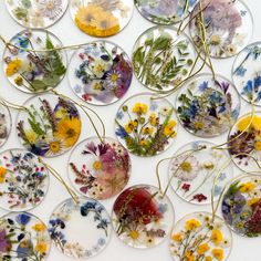 a collection of pressed glass flowers arranged in rows on a white surface with yellow, blue and purple flowers