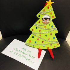 a paper christmas tree sitting on top of a black chair next to a white sign