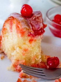 a piece of cake with cherries on it and a fork in front of it