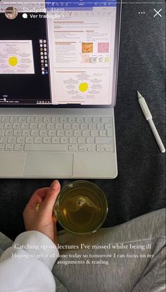 a person is sitting in front of a laptop and holding a glass with tea on it