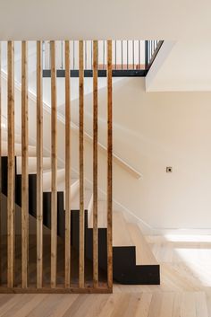 an empty room with wooden stairs and black handrails on the wall, in front of a white staircase