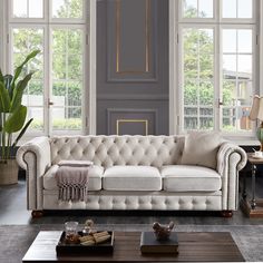 a living room filled with lots of furniture next to large windows and potted plants