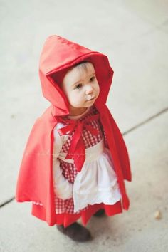 a small child wearing a red cape and dress