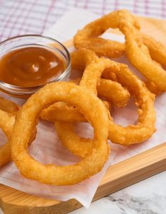 onion rings with dipping sauce on a cutting board