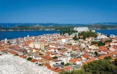 an aerial view of a city with red roofs and blue water in the back ground