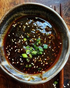 a bowl filled with sauce and vegetables on top of a wooden table