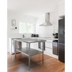 an empty kitchen with stainless steel appliances and wood floors