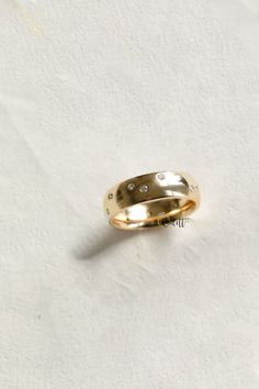 two gold wedding bands with diamonds on them sitting on a white surface in front of a wall