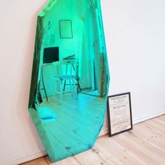 a mirror that is on the ground in front of a wall with a desk and chair