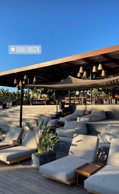 an outdoor seating area with couches, tables and umbrellas