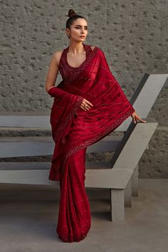 a woman in a red sari is sitting on a bench and posing for the camera