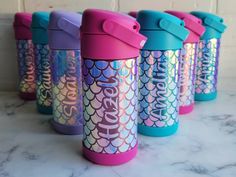 thermos cups are lined up in different colors and designs on a marble counter