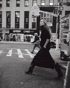 a woman walking across a street in front of a tall building with the words lie studio on it