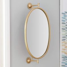 an oval mirror mounted to the side of a door with two brass knobs on it