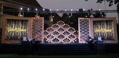 an outdoor stage set up for a wedding with lights and curtains on the front door