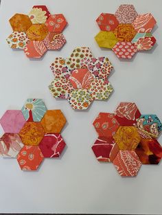 four hexagons made out of different colored papers on a white table top