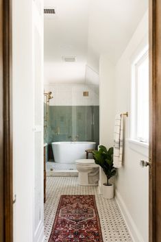 a bathroom with a rug on the floor and a bathtub in the corner next to it