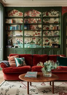 a living room with red couches and green bookshelves