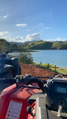 two atvs parked next to each other in front of a body of water on a sunny day