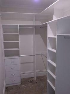 an empty walk in closet with white shelving