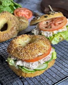 two bagels with tomatoes, lettuce and tomato on them sitting on a cooling rack