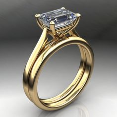 a yellow gold engagement ring with an emerald cut diamond in the center, on a white background