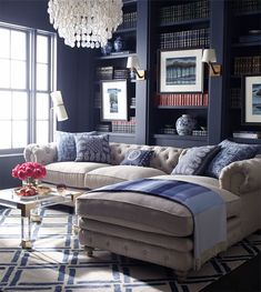 a living room filled with furniture and a chandelier hanging above the couches