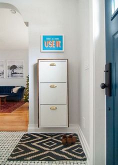 a white cabinet sitting in the corner of a room next to a blue door and rug