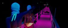 a woman in a bodysuit is walking down a ramp at night with her back turned to the camera