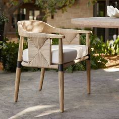 a wooden chair sitting on top of a cement floor next to a table and chairs