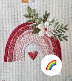 the embroidery pattern shows a rainbow with flowers on it and hearts in the bottom right corner