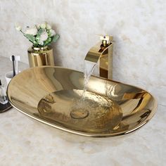 a bathroom sink with two faucets and a vase filled with flowers next to it