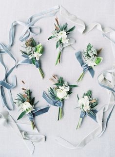 wedding bouquets arranged in the shape of a circle on a white tablecloth with blue ribbons