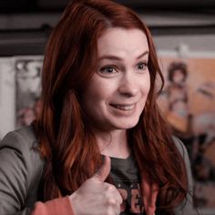 a woman with red hair giving the thumbs up sign