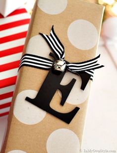 a gift wrapped in brown paper with a black letter on it next to a red and white striped present box