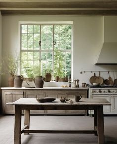 a table in a kitchen with pots and pans on top of it next to a window