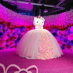 a hello kitty wedding dress is displayed in front of pink and purple flowered walls