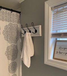 a bathroom with a shower curtain, towel rack and window sill in the corner