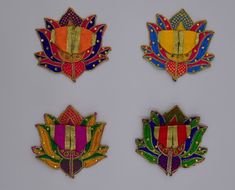 four different colored brooches with designs on them