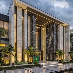 the entrance to a modern building with palm trees and lights on it's sides