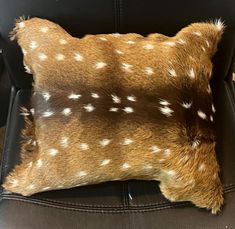 a brown and white deer print pillow sitting on top of a black chair