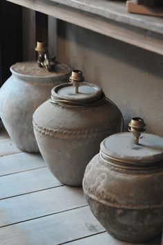 three large pots sitting on top of a wooden floor