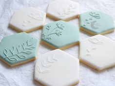 six decorated cookies sitting on top of a white tablecloth covered in frosted icing