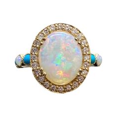 DeKara Designs Collection Metal- 18K Yellow Gold, .750. Stones- Center Features an Oval Fiery Australian Opal Cabochon Cut 12 x 10 MM 2.20-2.50 Carats, Four Marquise Turquoise, Two Round Opals, 30 Round Diamonds F-G Color VS2 Clarity, 0.40 Carats. Size- 4-12 Beautiful Handmade Art Deco Inspired Turquoise Diamond Halo Opal Engagement Ring Made in 18K Yellow Gold. This ring features a beautiful 12 x 10 oval shaped Australian Opal that is professionally set in between four double prongs. The opal is surrounded by 24 round fiery diamonds that are all professionally pave set. The shank features two marquise shaped sleeping beauty turquoise that are burnish set separated by one round round Australian opal, finally finishing off with three pave set round diamonds. The shank has milgrain work to f Turquoise Oval Multi-stone Opal Ring, Turquoise Multi-stone Round Opal Ring, Gold Oval Multi-stone Turquoise Ring, Gold Oval Turquoise Multi-stone Ring, Gold Turquoise Multi-stone Oval Ring, Yellow Gold Oval Turquoise Ring With Gemstone Accents, Yellow Gold Turquoise Ring With Gemstone Accents, Luxury Multi-stone Turquoise Round Ring, Fine Jewelry Multi-stone Turquoise Ring In Yellow Gold