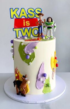 a birthday cake decorated with toy figures and the words kass is two on top